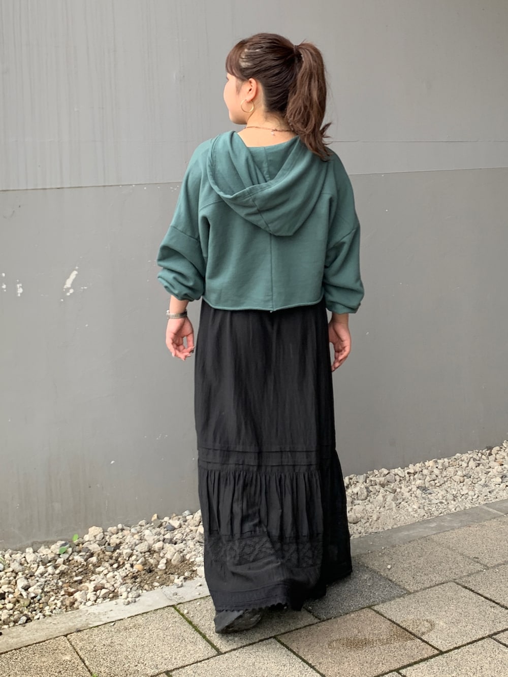 グリーン系のパーカー、ブラック系のスカートを着用したレディースの夏コーディネートの3枚目の写真