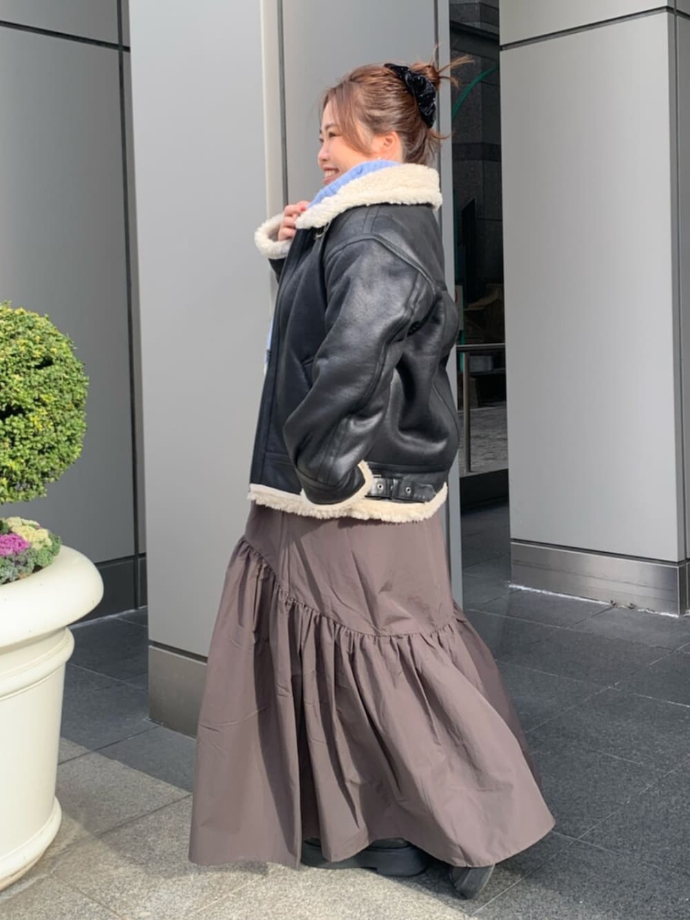 グレー系のスカート、ブラック系のブルゾン、ブルー系のニット/セーターを着用したレディースの冬コーディネートの2枚目の写真