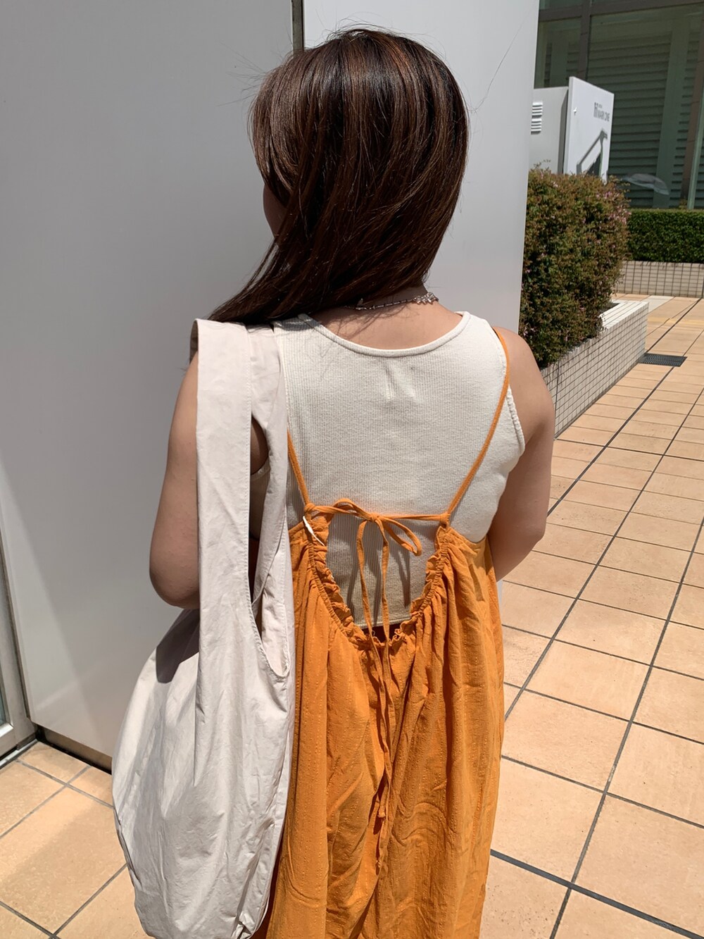 オレンジ系のワンピース、ホワイト系のハンドバッグを着用したレディースの夏コーディネートの4枚目の写真