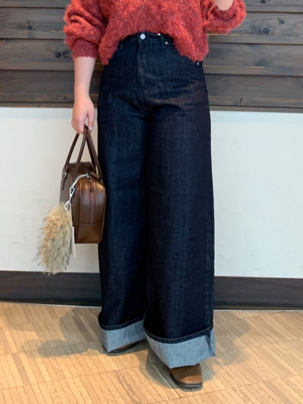 レッド系のニット/セーター、ブルー系のデニムパンツ、ブラウン系のハンドバッグを着用したレディースの秋コーディネートの5枚目の写真