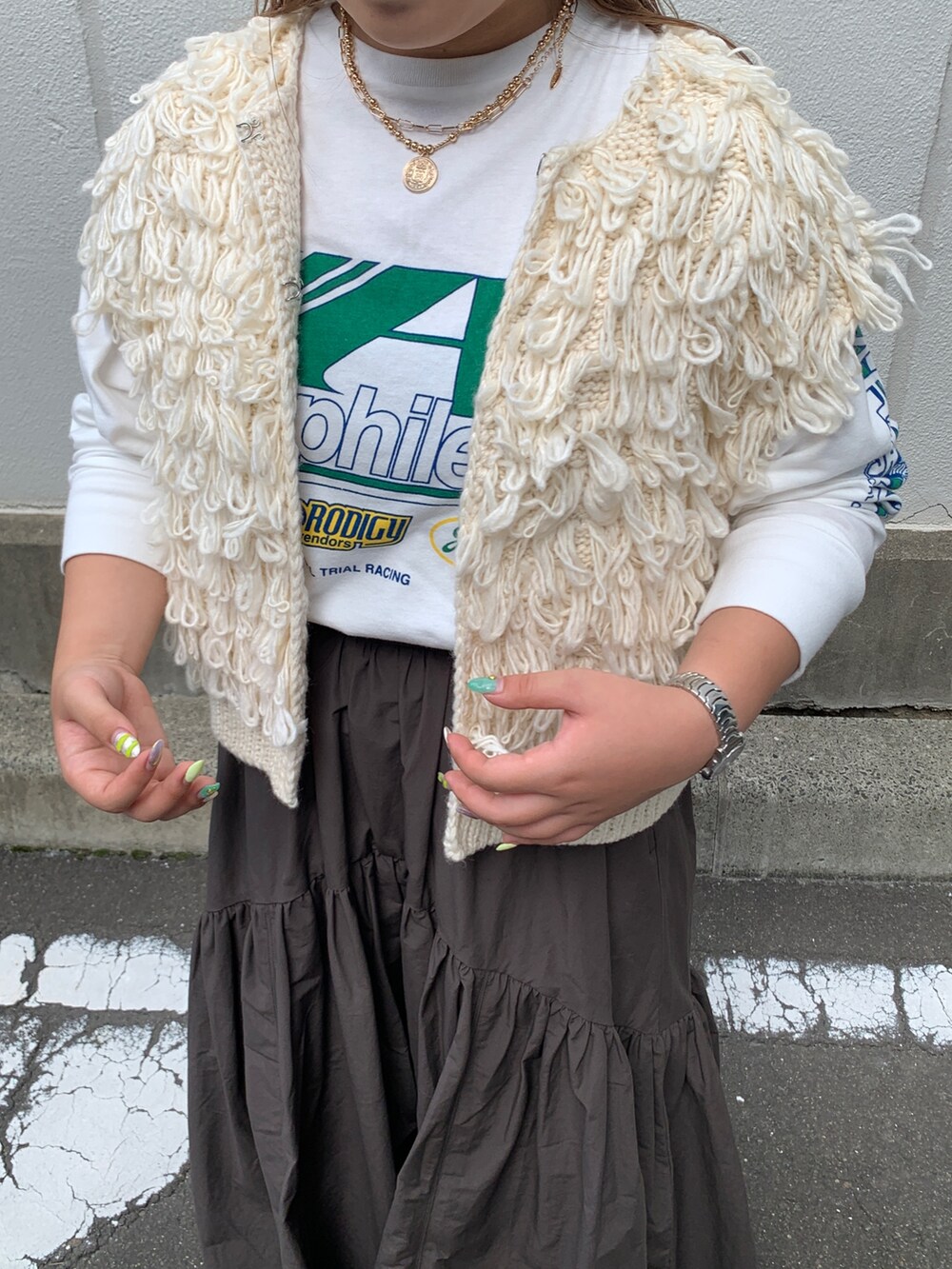 ホワイト系のTシャツ/カットソー、ホワイト系のベスト、グレー系のスカートを着用したレディースの秋コーディネートの4枚目の写真