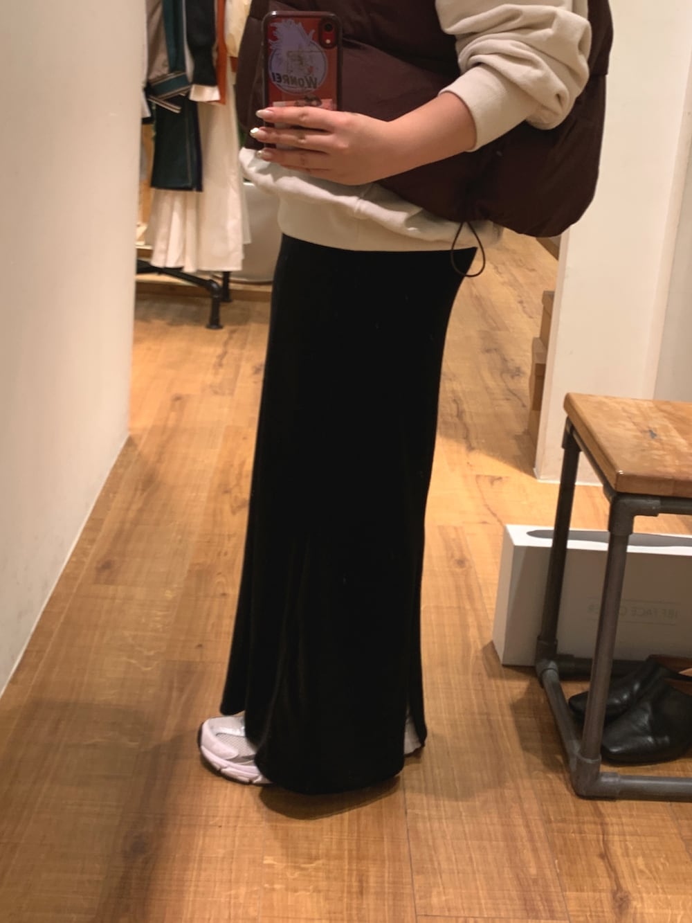 ブラウン系のダウンベスト、ホワイト系のパーカー、ブラック系のスカートを着用したレディースの秋コーディネートの6枚目の写真