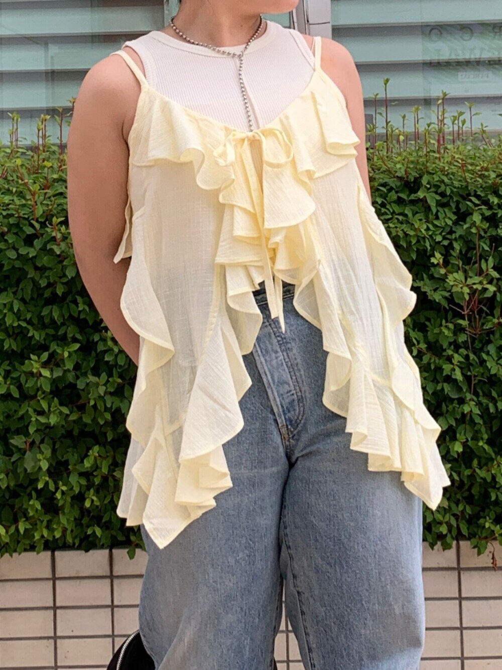 ブルー系のデニムパンツ、イエロー系のキャミソール、ホワイト系のタンクトップを着用したレディースの夏コーディネートの4枚目の写真