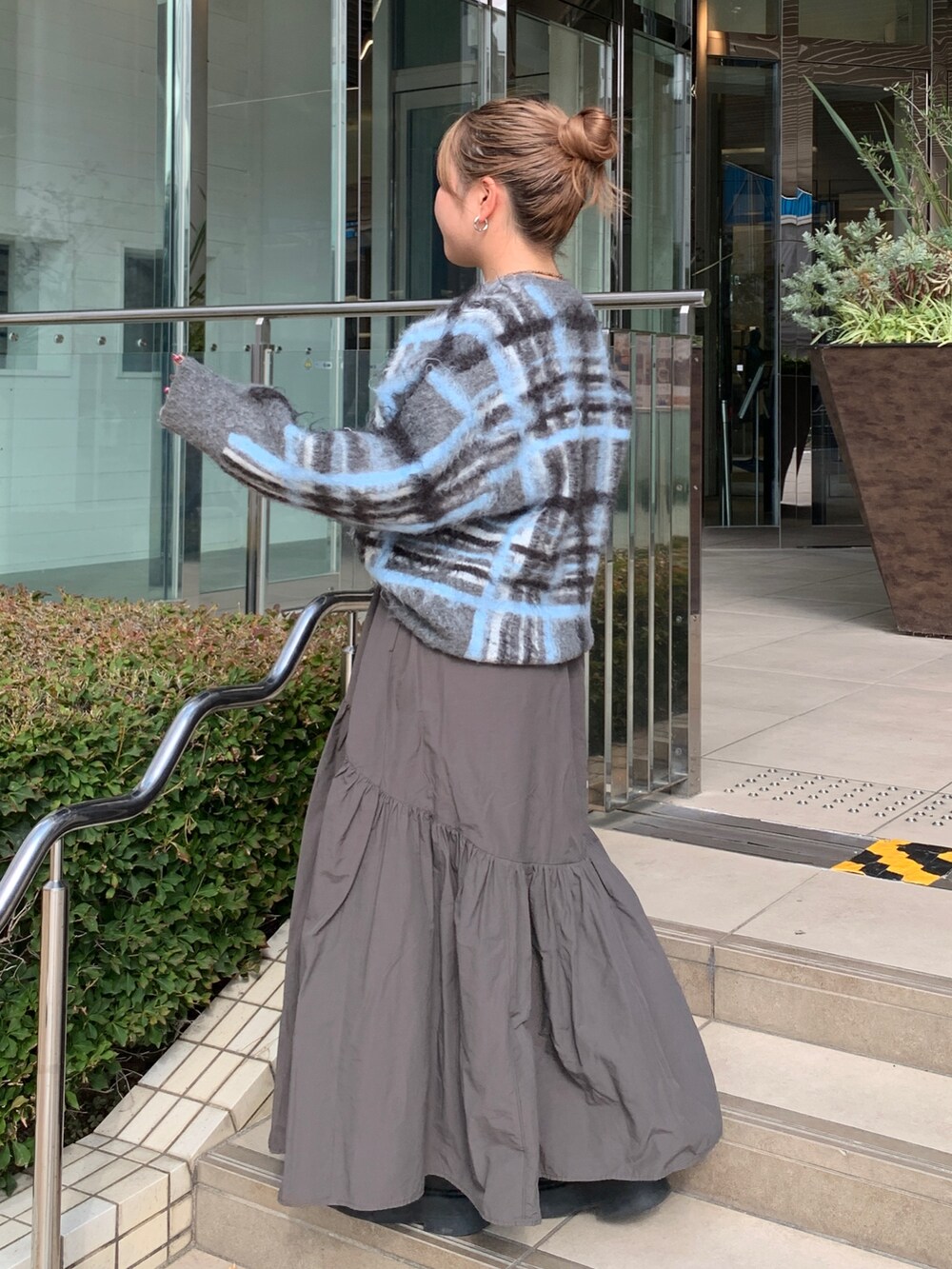 グレー系のニット/セーター、グレー系のスカートを着用したレディースの秋コーディネートの2枚目の写真