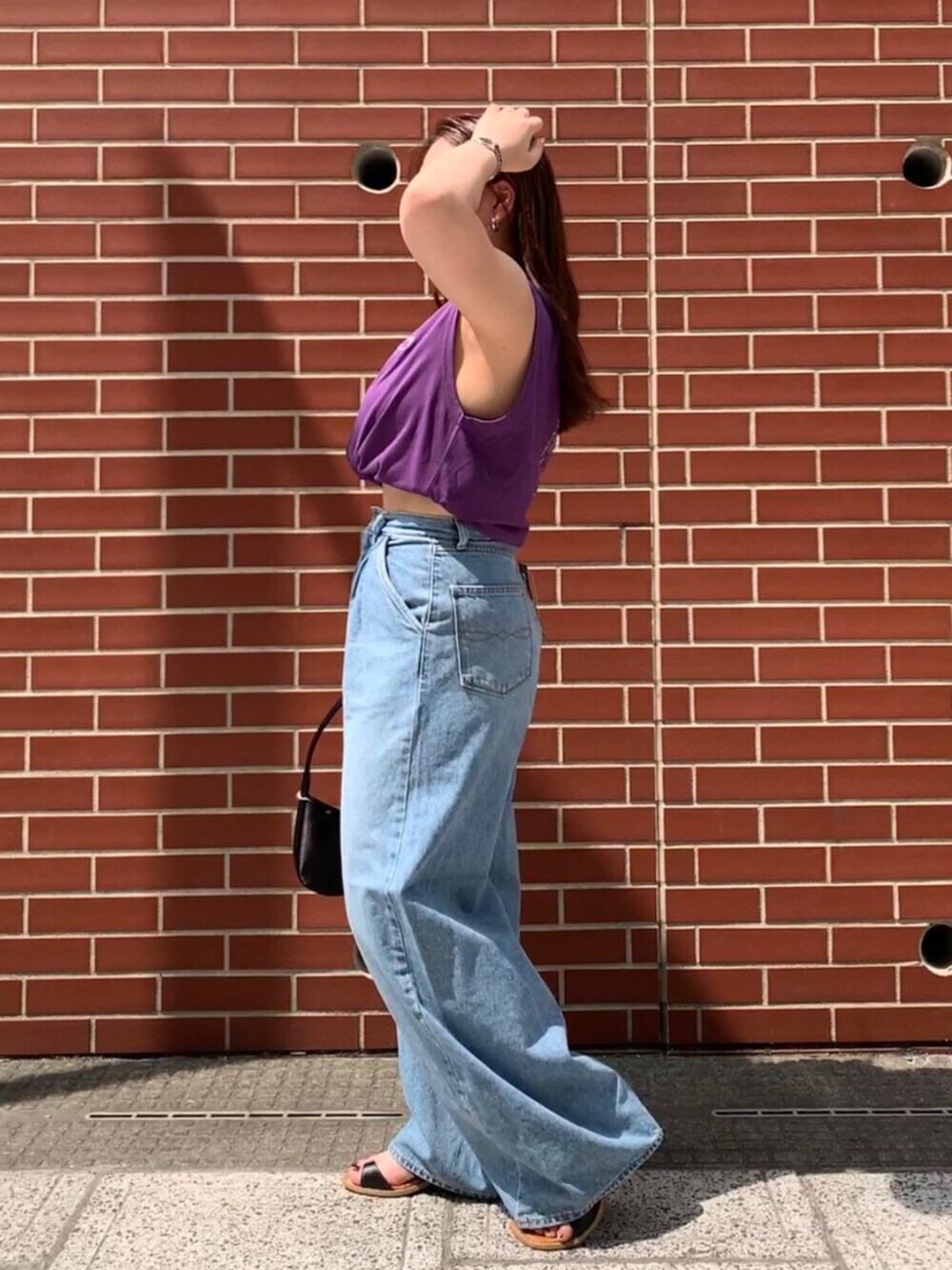パープル系のタンクトップ、ブルー系のデニムパンツを着用したレディースの夏コーディネートの2枚目の写真