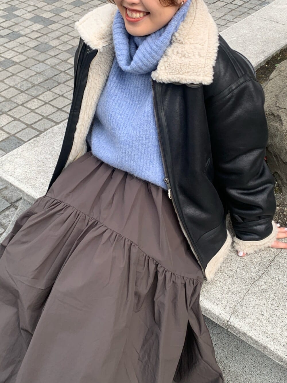 グレー系のスカート、ブラック系のブルゾン、ブルー系のニット/セーターを着用したレディースの冬コーディネートの4枚目の写真