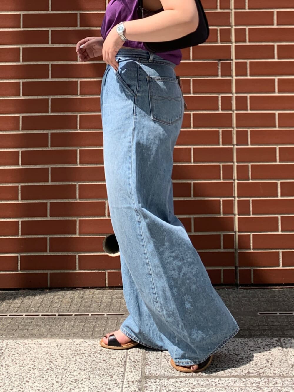 パープル系のタンクトップ、ブルー系のデニムパンツを着用したレディースの夏コーディネートの6枚目の写真