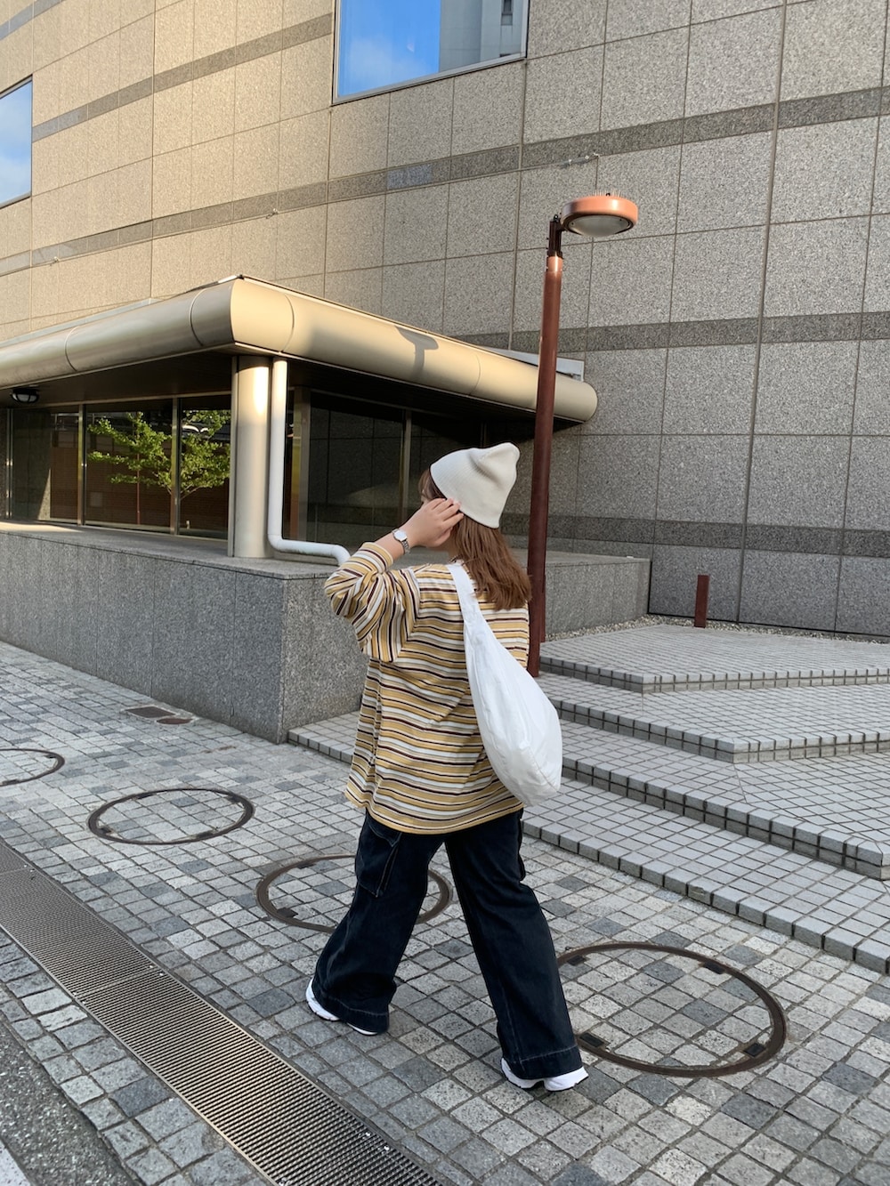 イエロー系のTシャツ/カットソー、ブラック系のデニムパンツ、ホワイト系のショルダーバッグを着用したレディースの秋コーディネートの2枚目の写真