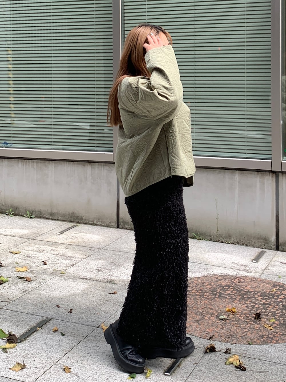 グリーン系のブルゾン、ホワイト系のTシャツ/カットソー、ブラック系のスカートを着用したレディースの秋コーディネートの2枚目の写真