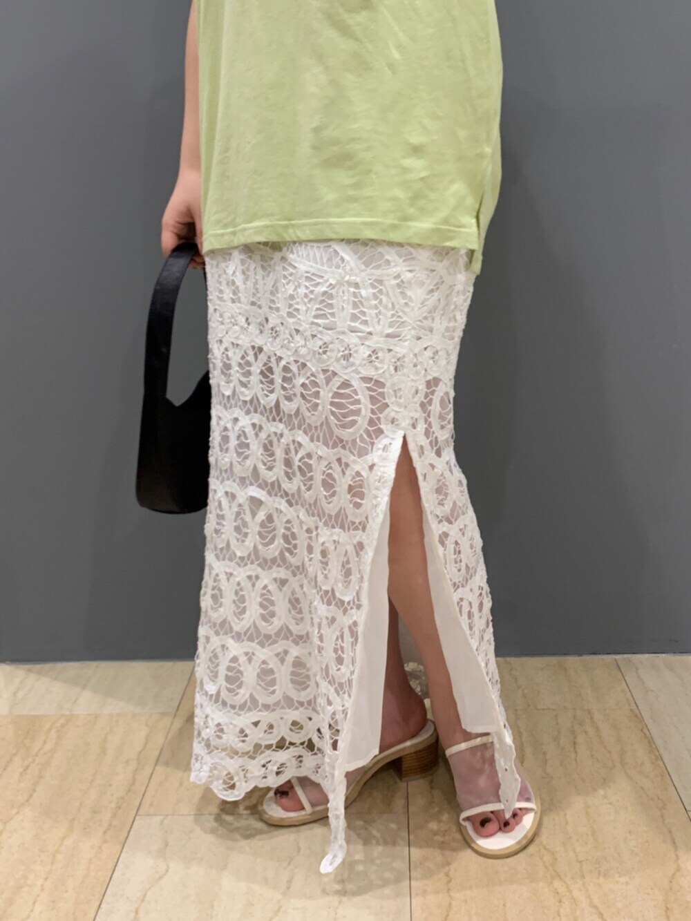 グリーン系のタンクトップ、ホワイト系のスカートを着用したレディースの夏コーディネートの6枚目の写真