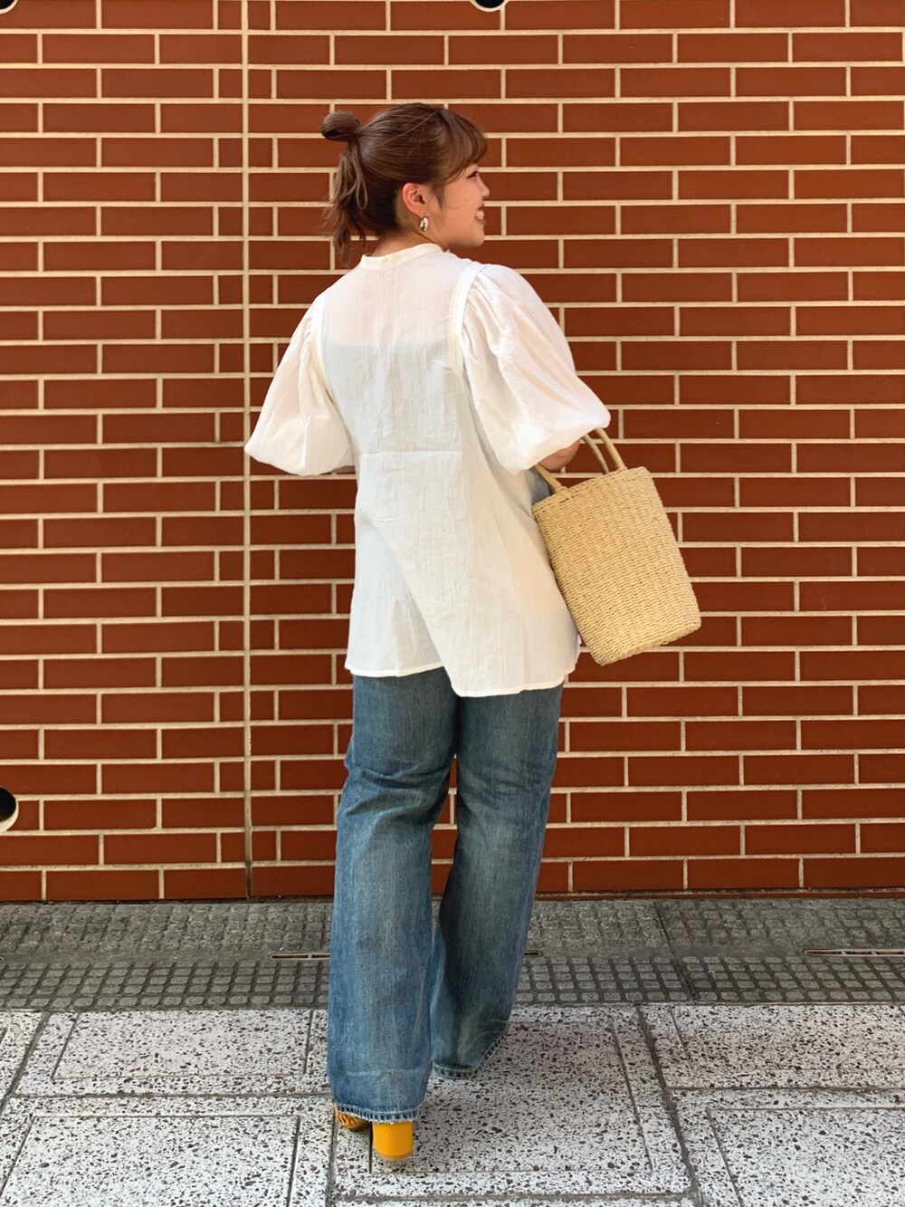 ブルー系のデニムパンツ、ベージュ系のかごバッグ、ホワイト系のシャツ/ブラウスを着用したレディースの夏コーディネートの3枚目の写真