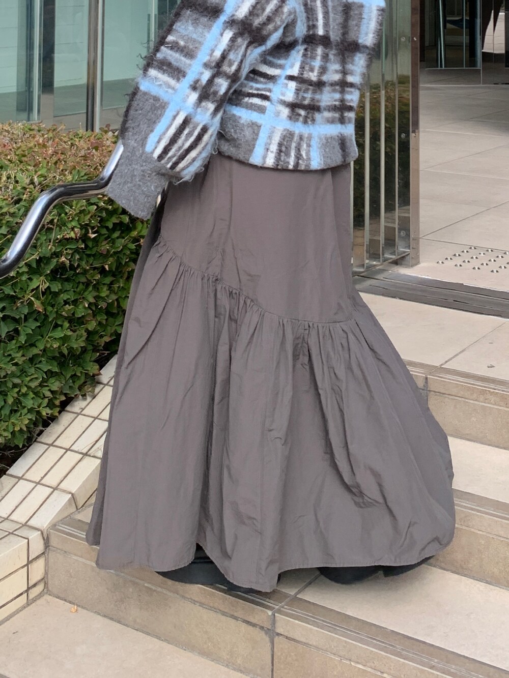 グレー系のニット/セーター、グレー系のスカートを着用したレディースの秋コーディネートの6枚目の写真