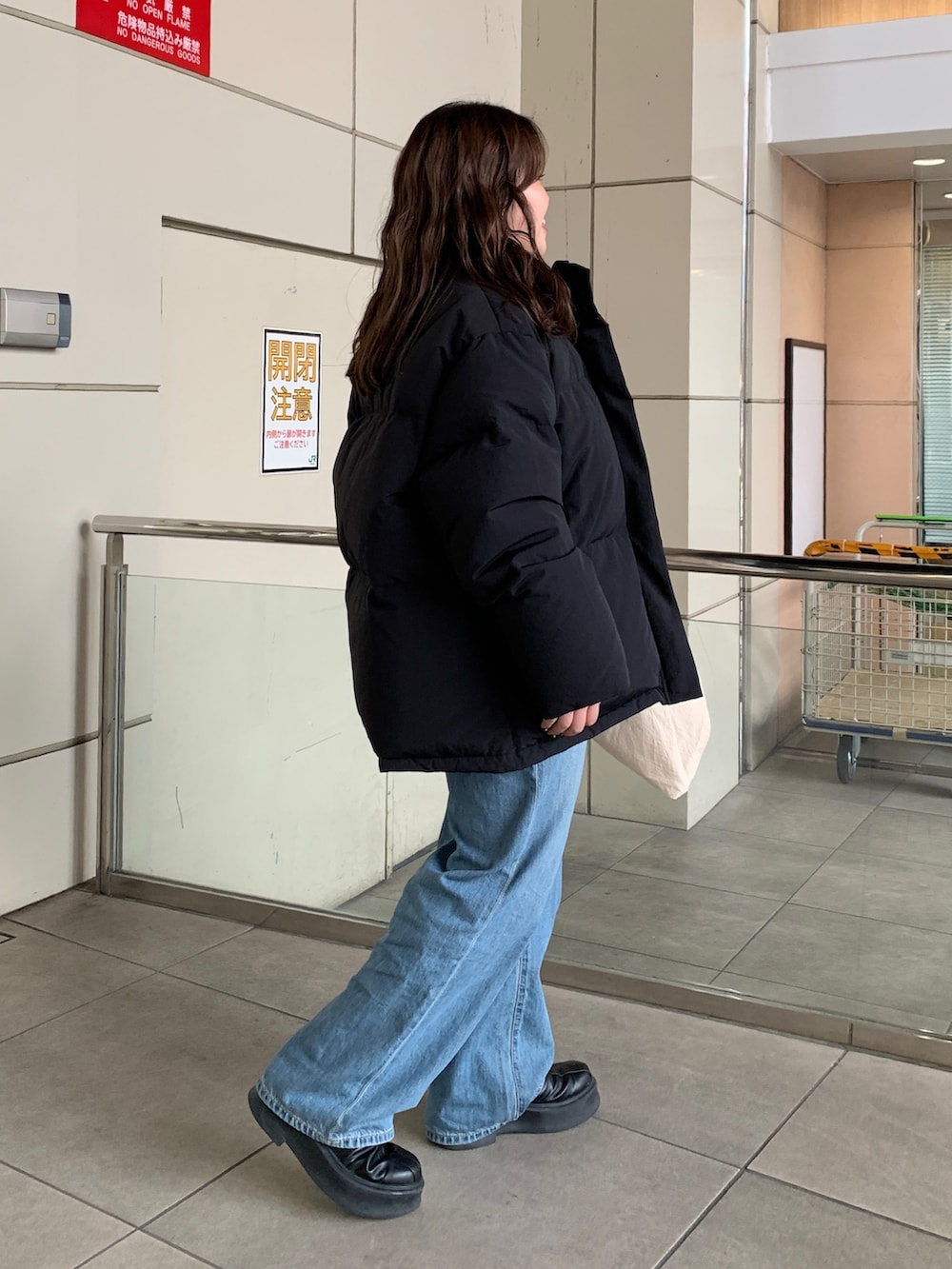 ブラック系のダウンジャケット/コート、グリーン系のニット/セーター、ブルー系のデニムパンツを着用したレディースの冬コーディネートの2枚目の写真