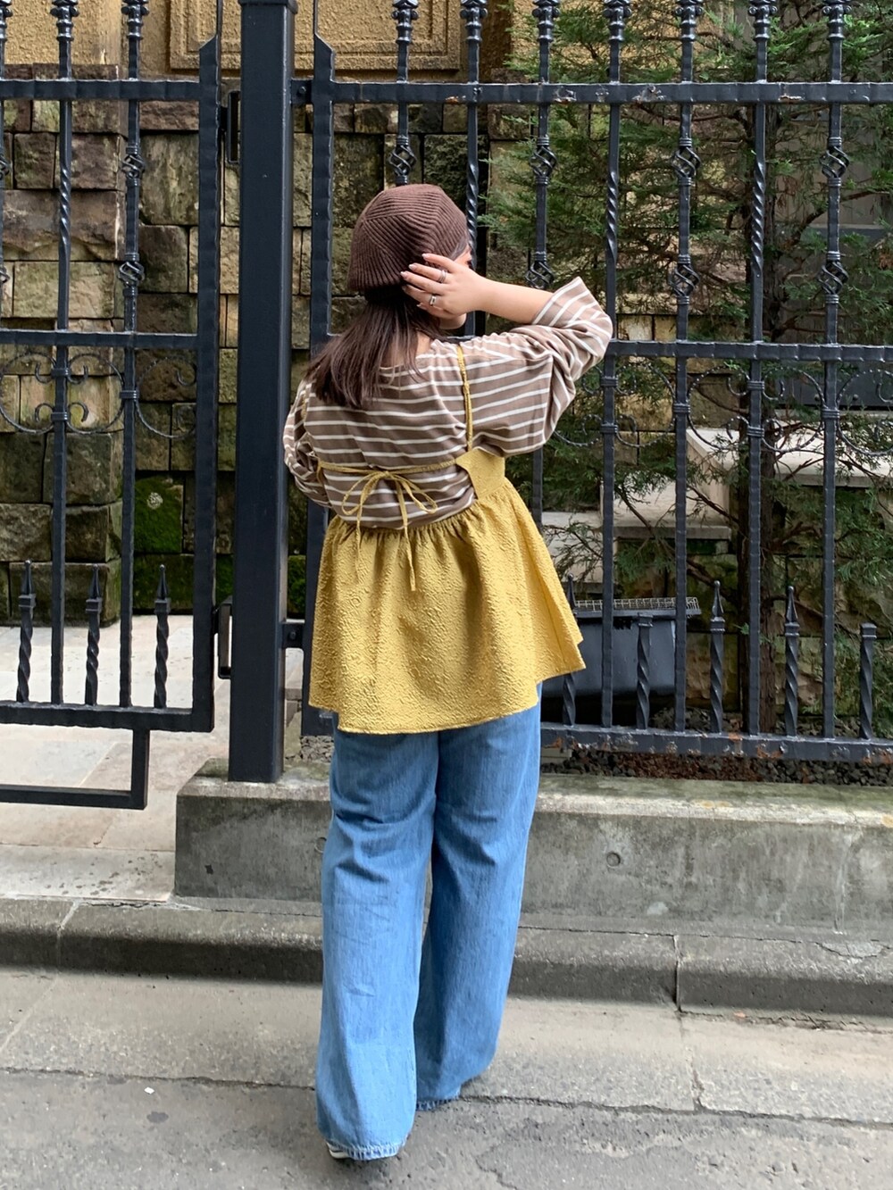 イエロー系のキャミソール、ブラウン系のTシャツ/カットソー、ブルー系のデニムパンツを着用したレディースの秋コーディネートの3枚目の写真