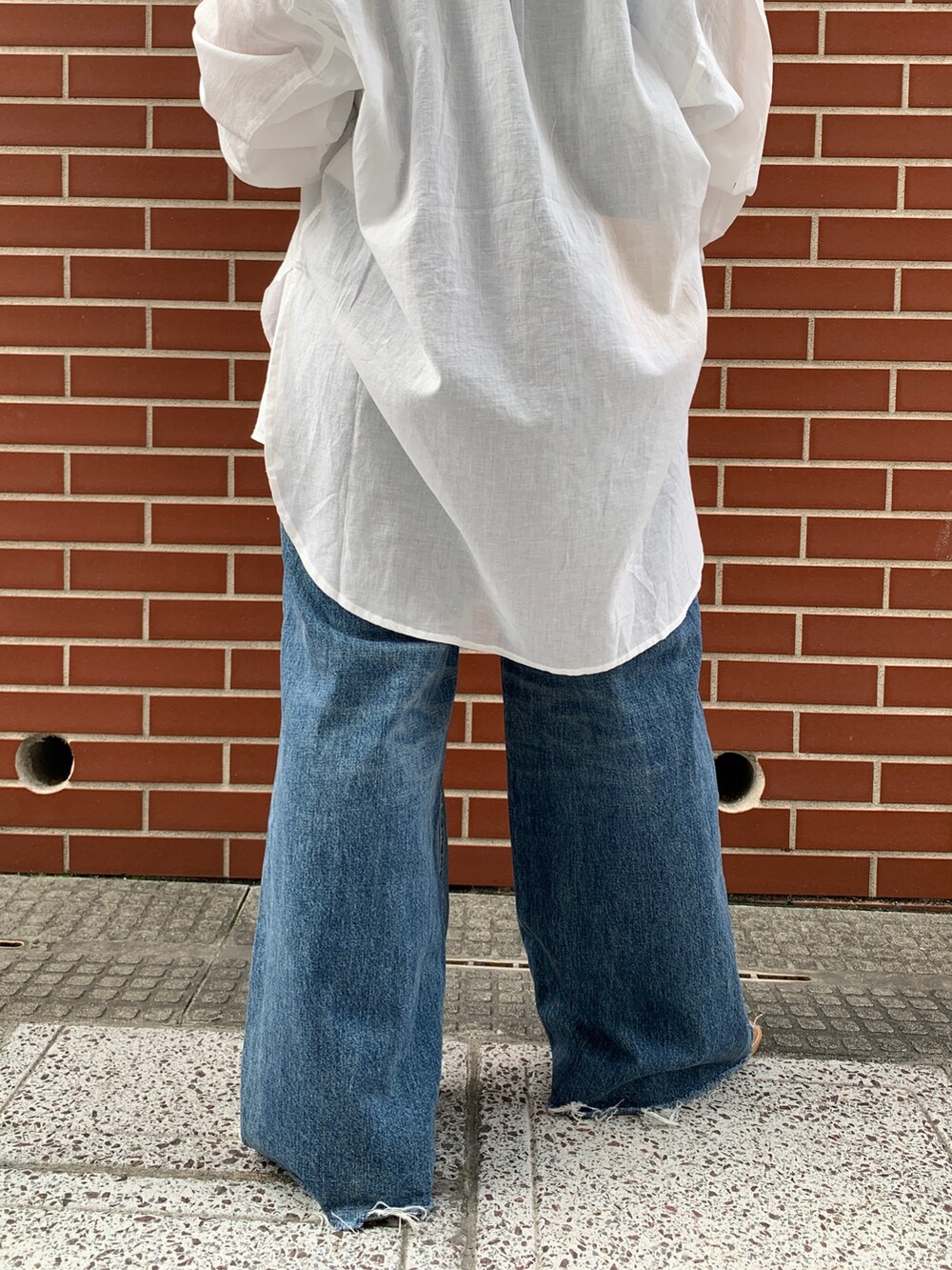 ブルー系のキャミソール、ホワイト系のシャツ/ブラウス、ブルー系のデニムパンツを着用したレディースの春コーディネートの8枚目の写真