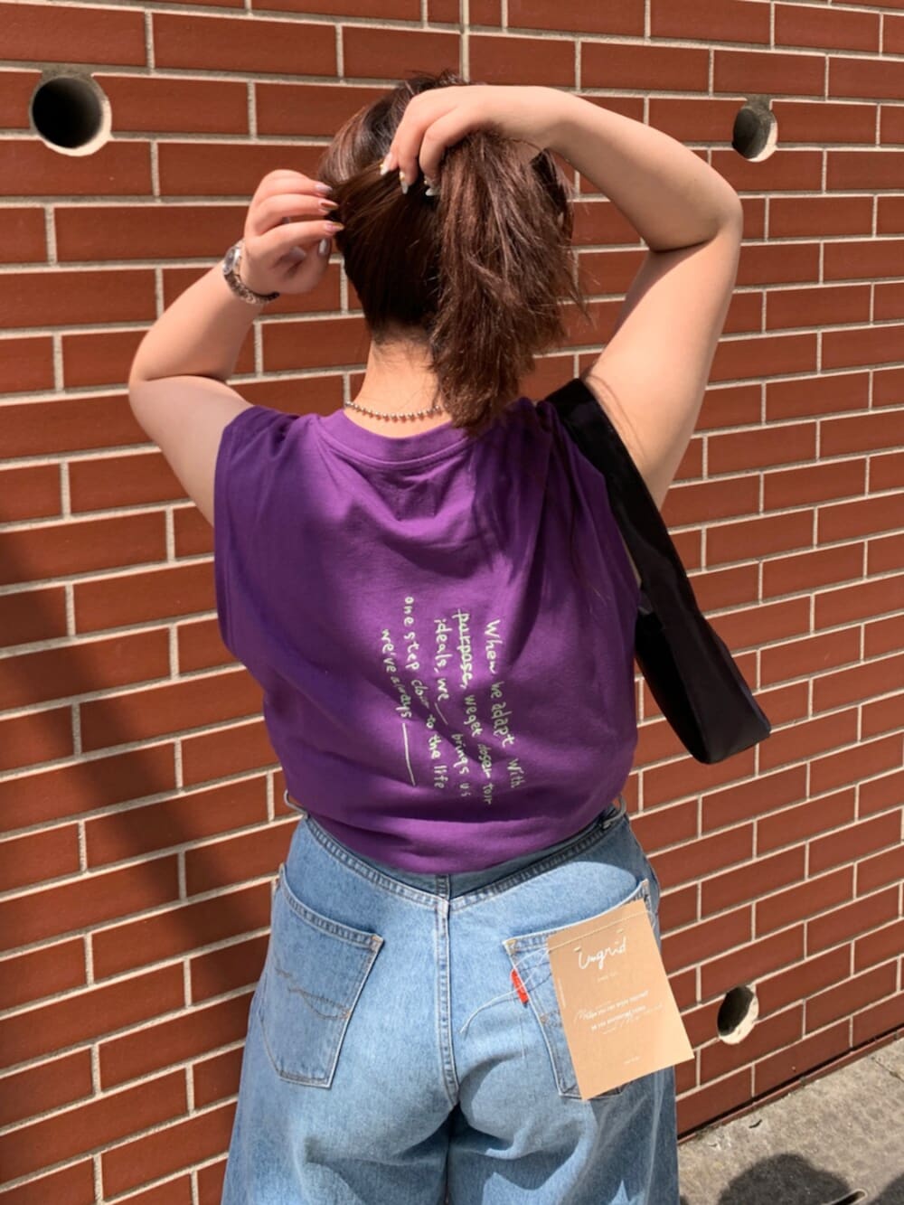 パープル系のタンクトップ、ブルー系のデニムパンツを着用したレディースの夏コーディネートの4枚目の写真