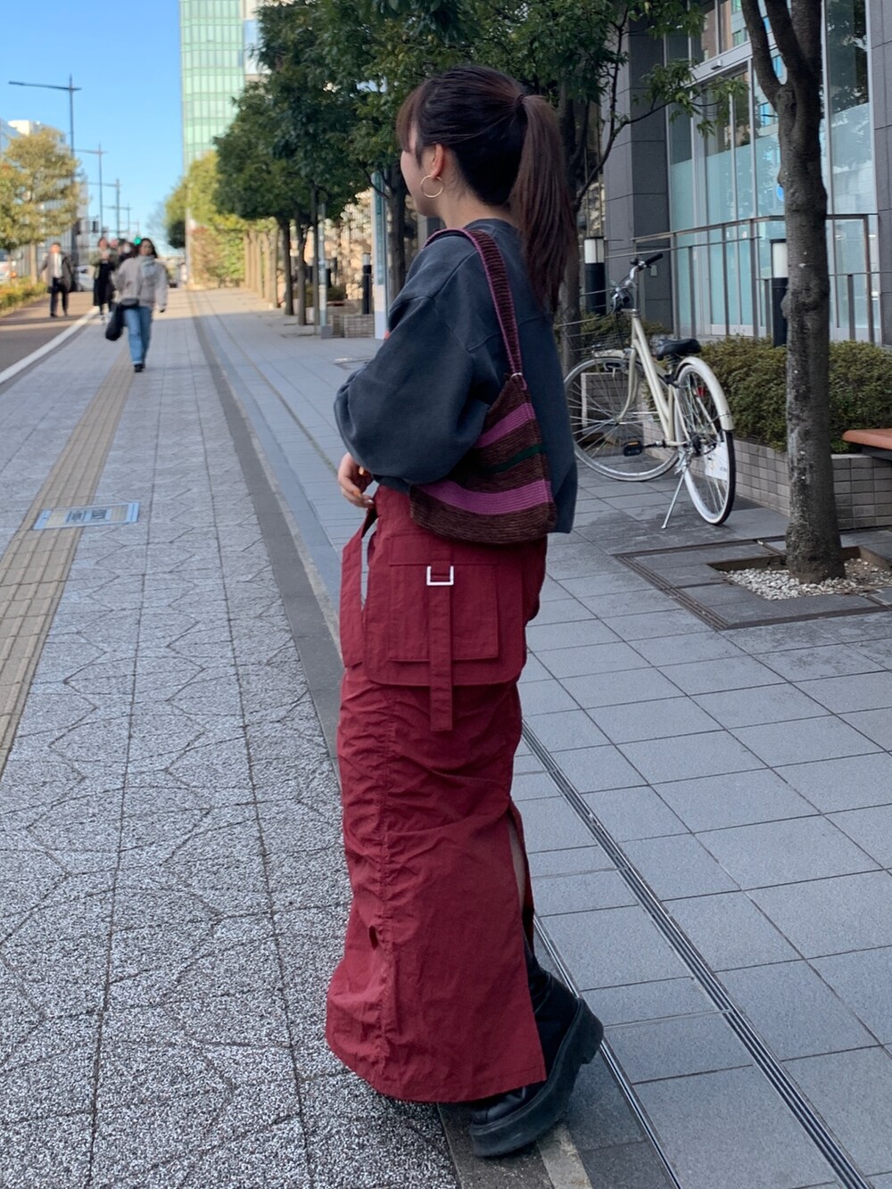 グレー系のスウェット、レッド系のスカート、ブラウン系のハンドバッグを着用したレディースの冬コーディネートの2枚目の写真