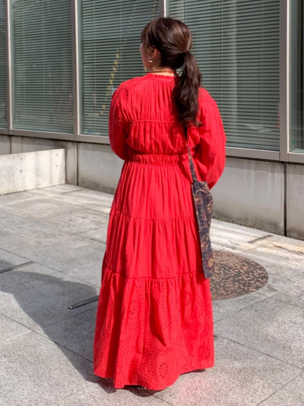 レッド系のワンピース、ブラック系のショルダーバッグ、レッド系のネックレスを着用したレディースの冬コーディネートの3枚目の写真