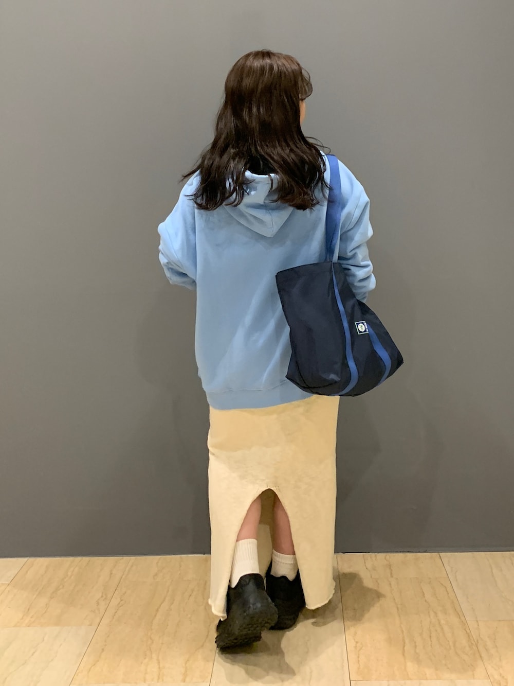 ブルー系のパーカー、ホワイト系のスカート、ブルー系のトートバッグを着用したレディースの冬コーディネートの3枚目の写真