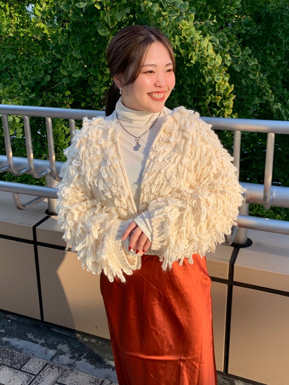 ホワイト系のカーディガン/ボレロ、ホワイト系のTシャツ/カットソー、オレンジ系のスカートを着用したレディースの冬コーディネートの4枚目の写真