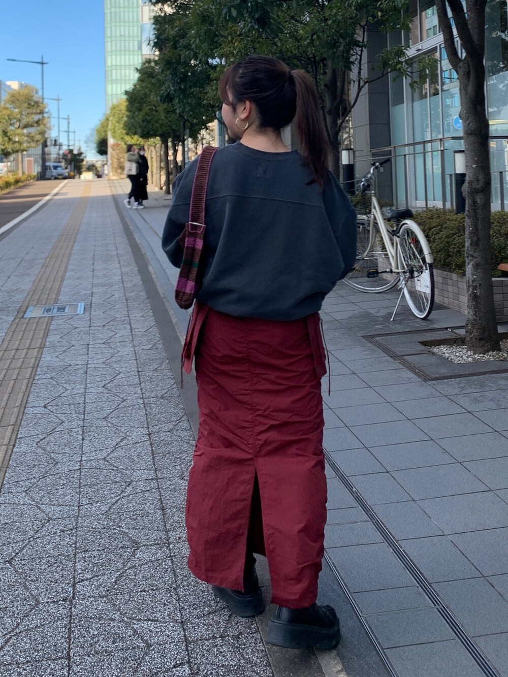 グレー系のスウェット、レッド系のスカート、ブラウン系のハンドバッグを着用したレディースの冬コーディネートの3枚目の写真