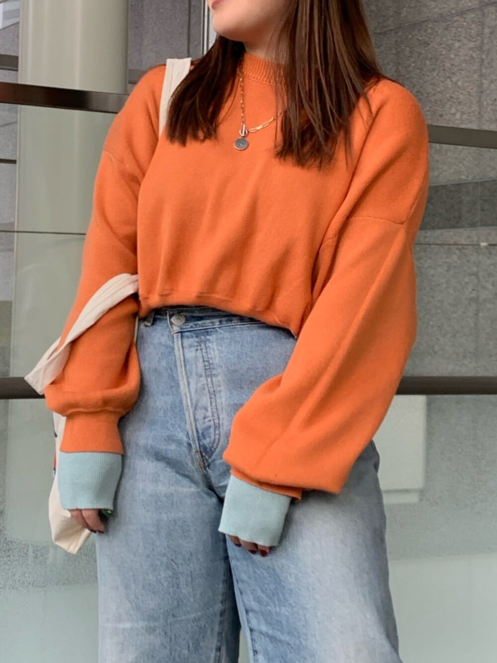 オレンジ系のニット/セーター、ブルー系のデニムパンツ、ホワイト系のトートバッグを着用したレディースの冬コーディネートの4枚目の写真