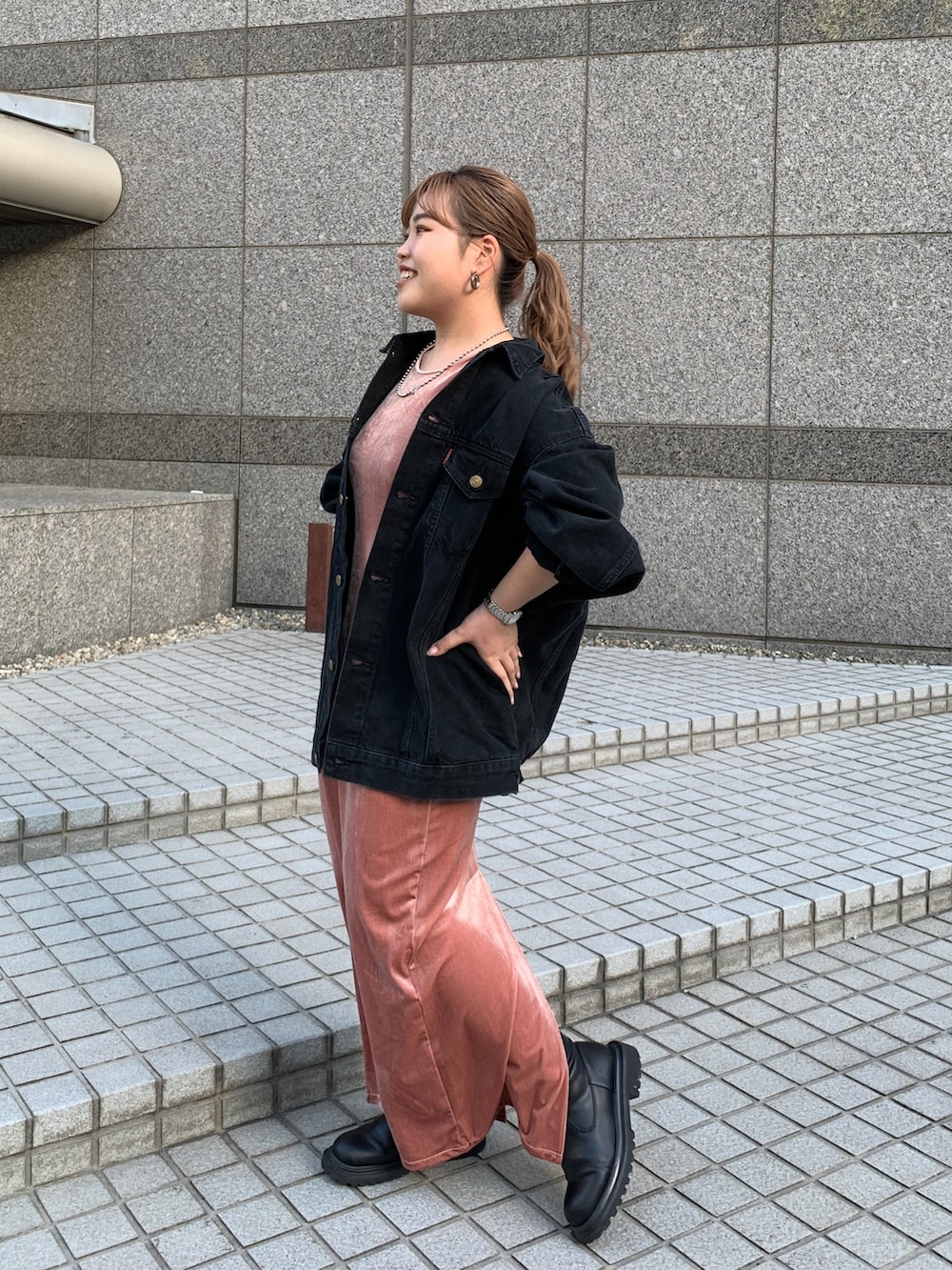 ブラック系のデニムジャケット、オレンジ系のワンピースを着用したレディースの秋コーディネートの2枚目の写真