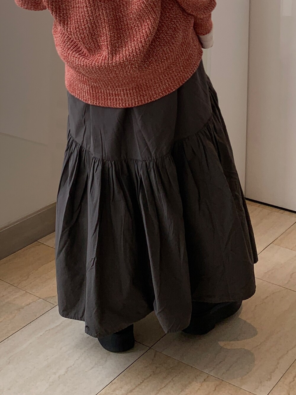 ピンク系のTシャツ/カットソー、オレンジ系のカーディガン/ボレロ、グレー系のスカートを着用したレディースの冬コーディネートの7枚目の写真