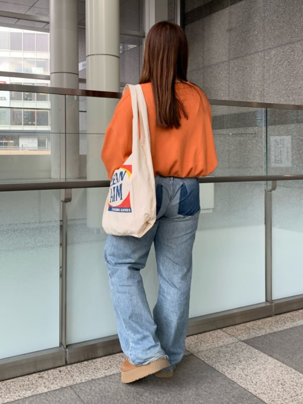 オレンジ系のニット/セーター、ブルー系のデニムパンツ、ホワイト系のトートバッグを着用したレディースの冬コーディネートの3枚目の写真