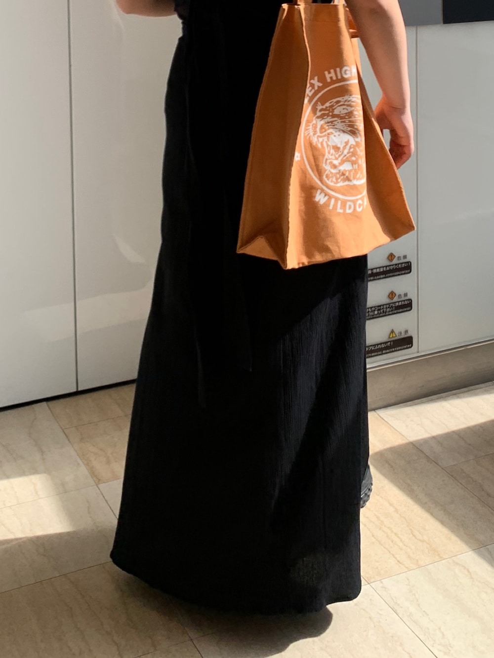 ブラック系のワンピース、オレンジ系のトートバッグを着用したレディースの春コーディネートの8枚目の写真