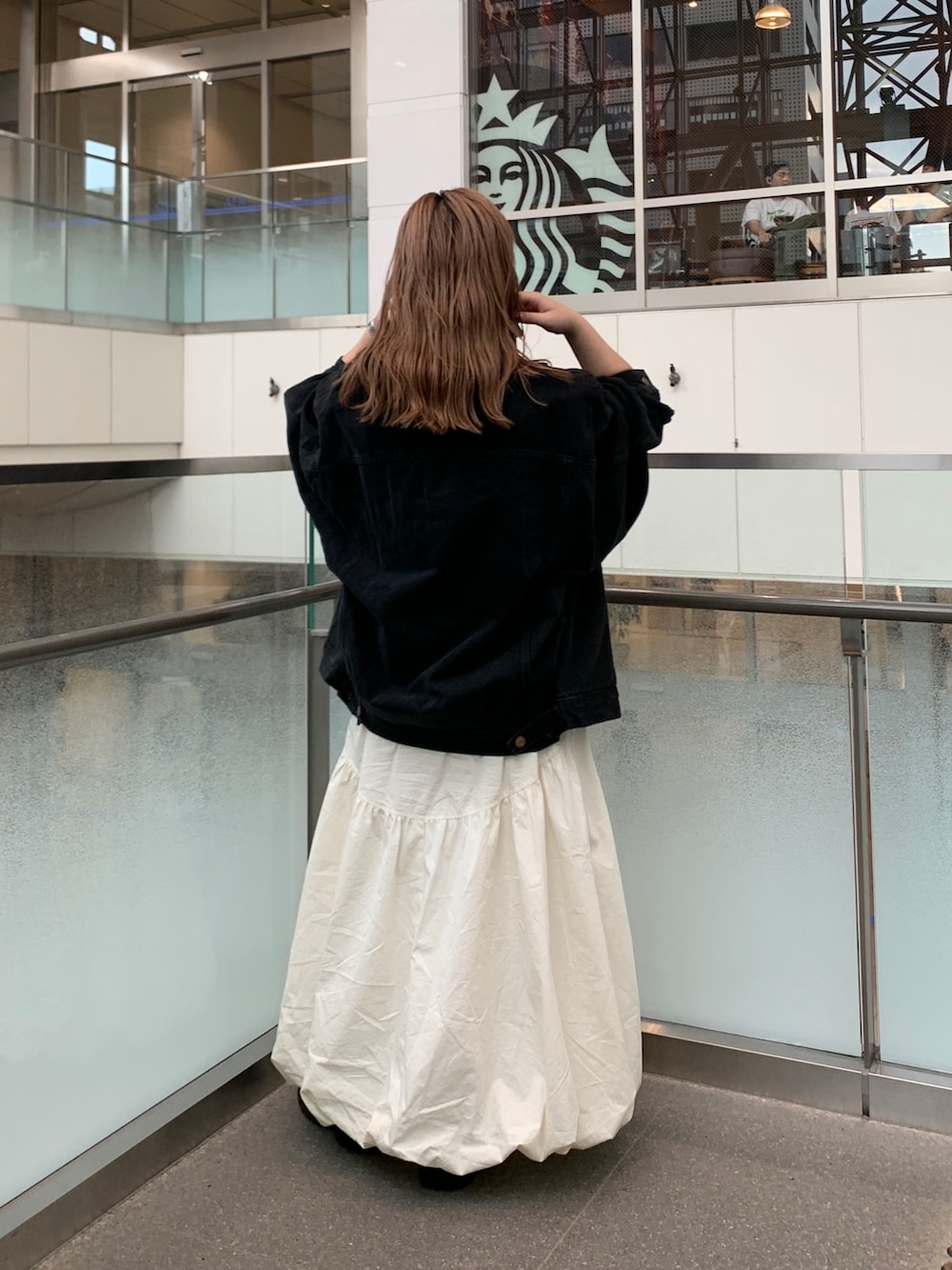 ブラック系のデニムジャケット、ピンク系のベスト、ホワイト系のキャミソールを着用したレディースの夏コーディネートの3枚目の写真