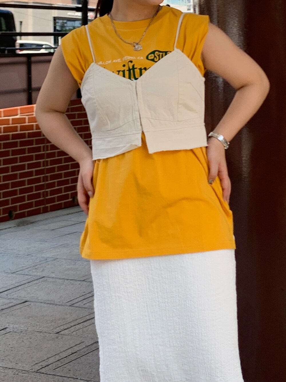 イエロー系のTシャツ/カットソー、ホワイト系のスカート、ホワイト系のキャミソールを着用したレディースの夏コーディネートの4枚目の写真