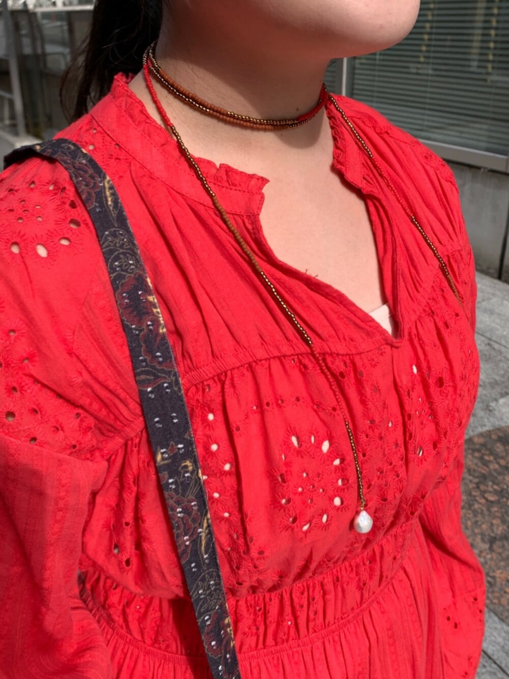 レッド系のワンピース、ブラック系のショルダーバッグ、レッド系のネックレスを着用したレディースの冬コーディネートの4枚目の写真