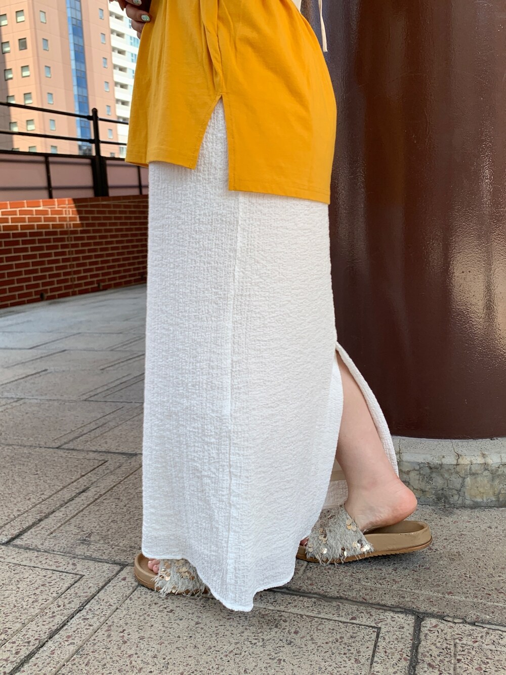 イエロー系のTシャツ/カットソー、ホワイト系のスカート、ホワイト系のキャミソールを着用したレディースの夏コーディネートの6枚目の写真