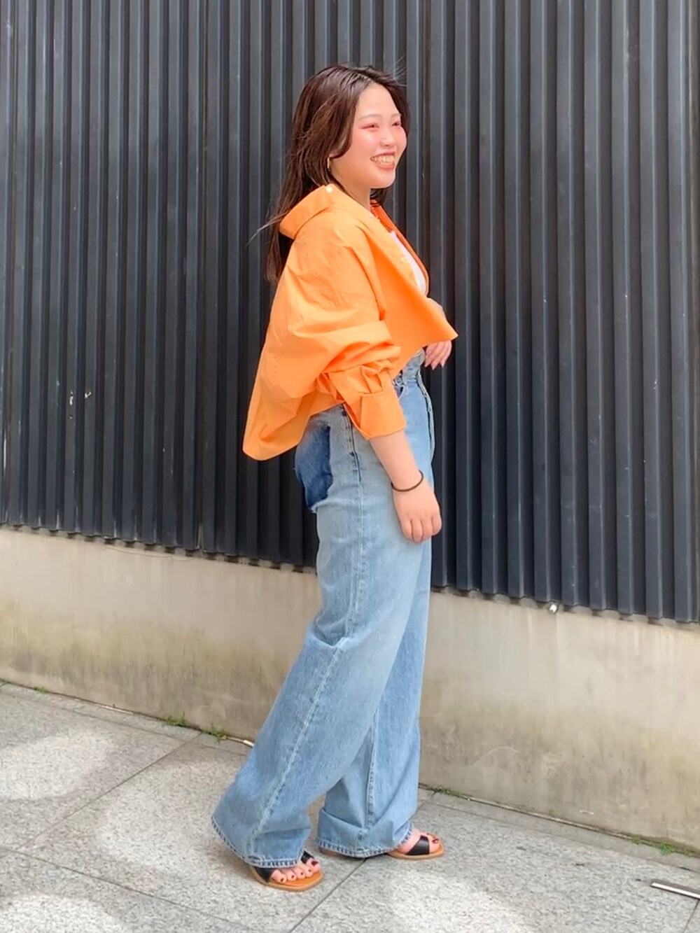 オレンジ系のシャツ/ブラウス、ホワイト系のキャミソール、ブルー系のデニムパンツを着用したレディースの春コーディネートの2枚目の写真