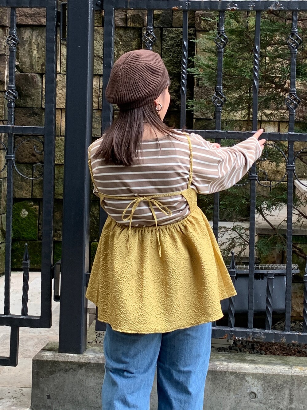 イエロー系のキャミソール、ブラウン系のTシャツ/カットソー、ブルー系のデニムパンツを着用したレディースの秋コーディネートの6枚目の写真