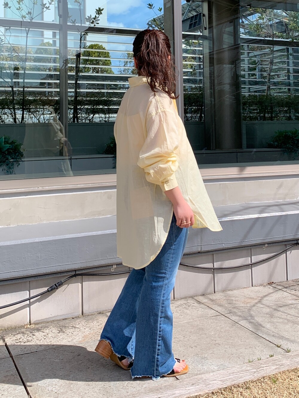 イエロー系のシャツ/ブラウス、ブルー系のデニムパンツ、ブラック系のサンダルを着用したレディースの春コーディネートの2枚目の写真