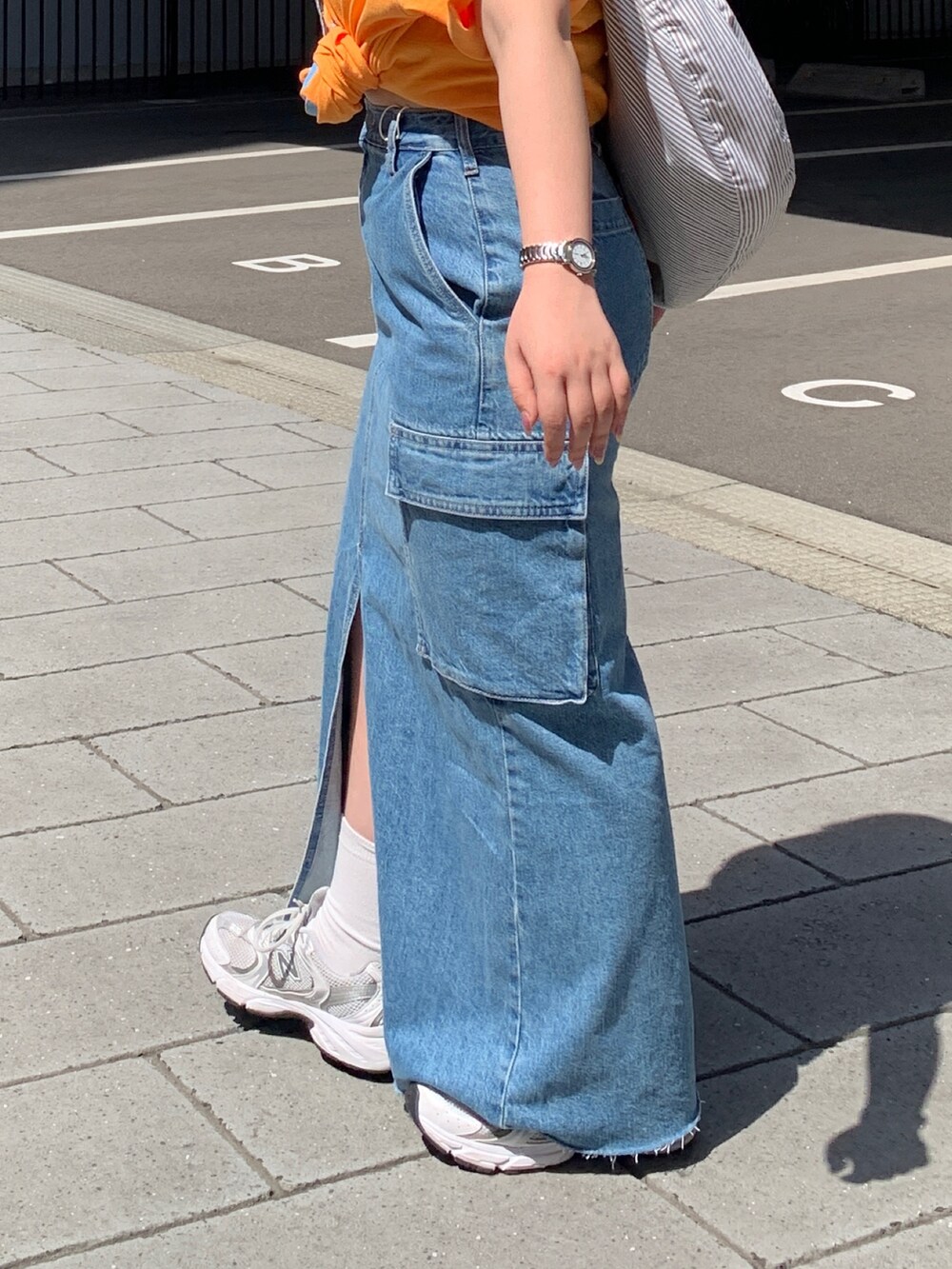 オレンジ系のTシャツ/カットソー、その他のショルダーバッグ、ブルー系のデニムスカートを着用したレディースの春コーディネートの6枚目の写真