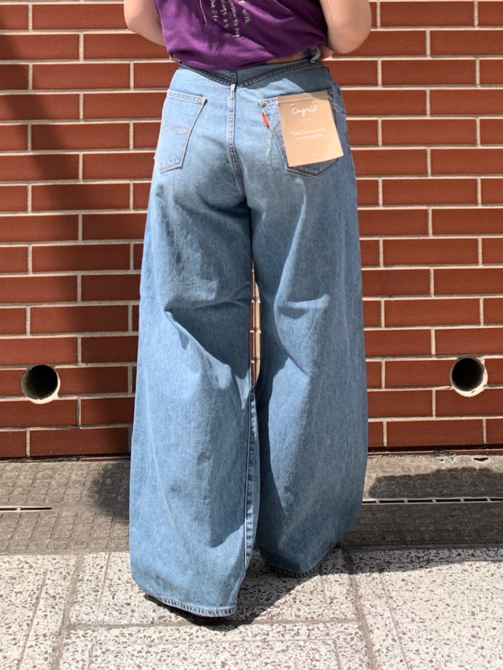 パープル系のタンクトップ、ブルー系のデニムパンツを着用したレディースの夏コーディネートの7枚目の写真