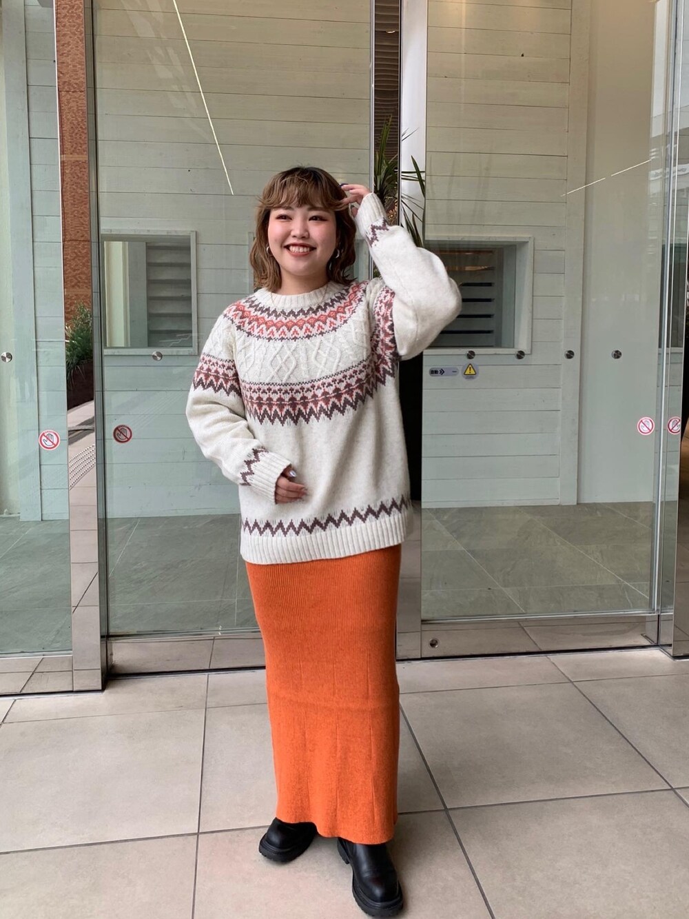 ブラウン系のムートンコート、オレンジ系のスカート、ホワイト系のニット/セーターを着用したレディースの冬コーディネートの3枚目の写真