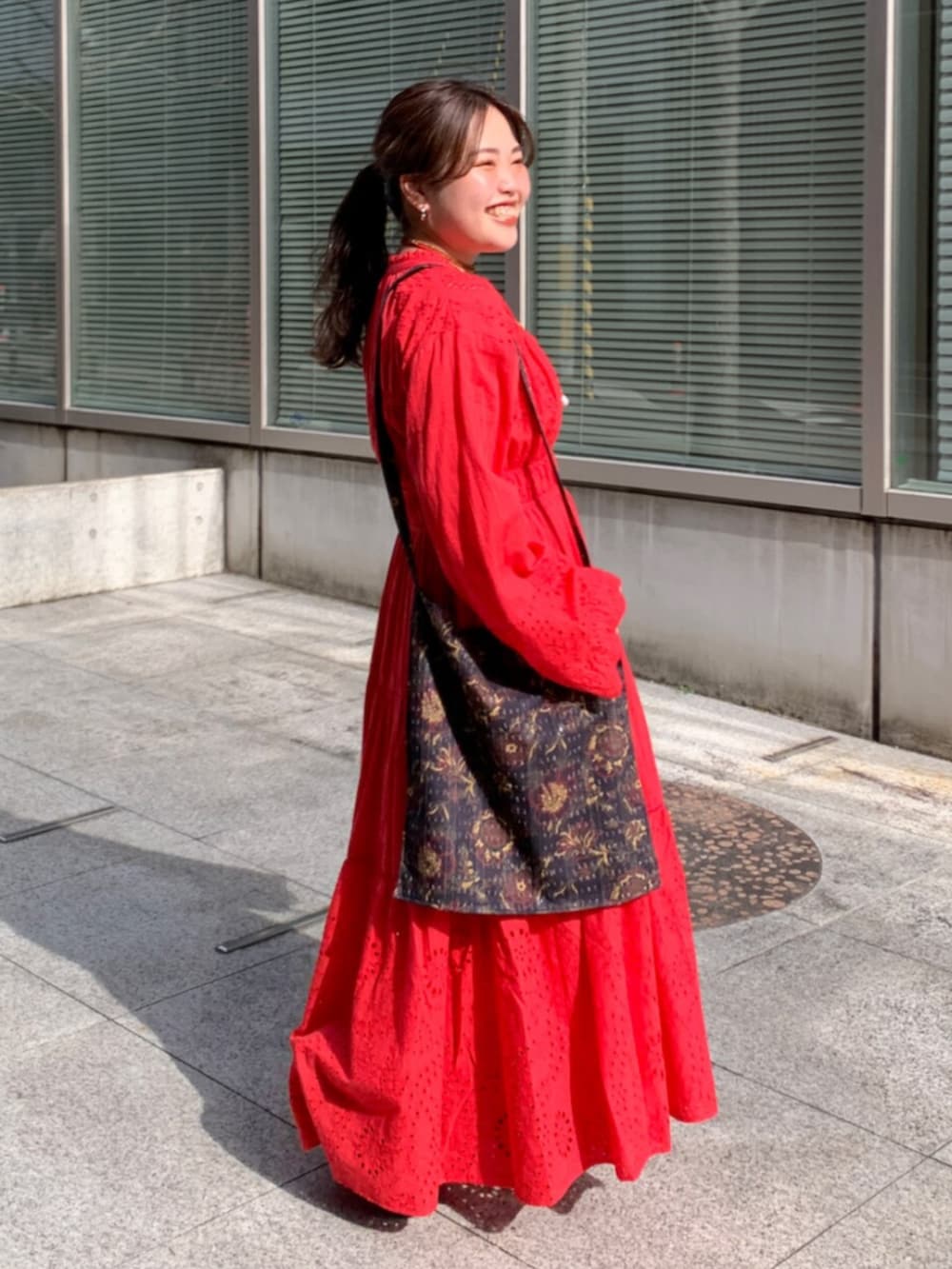 レッド系のワンピース、ブラック系のショルダーバッグ、レッド系のネックレスを着用したレディースの冬コーディネートの2枚目の写真