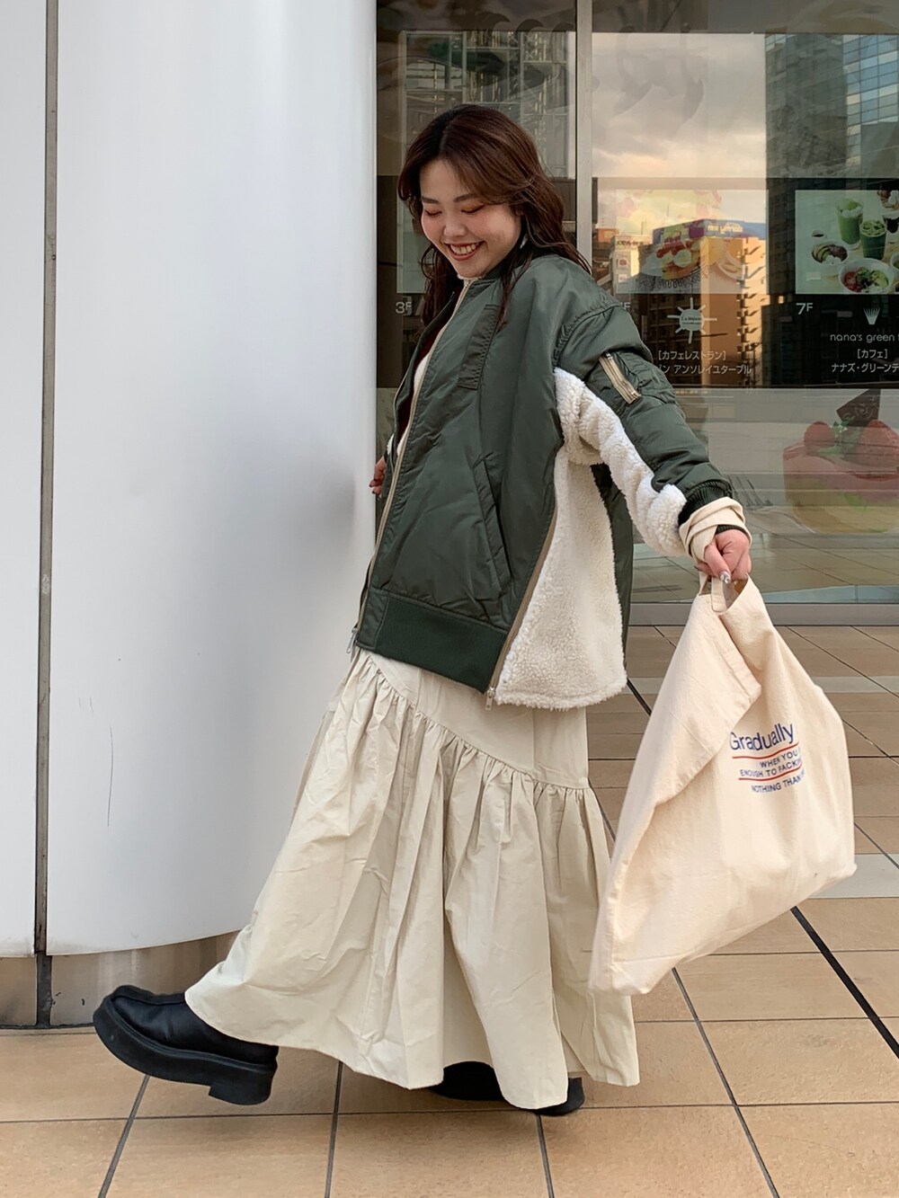 ホワイト系のスカート、ホワイト系のニット/セーター、グリーン系のMA-1を着用したレディースの冬コーディネートの2枚目の写真