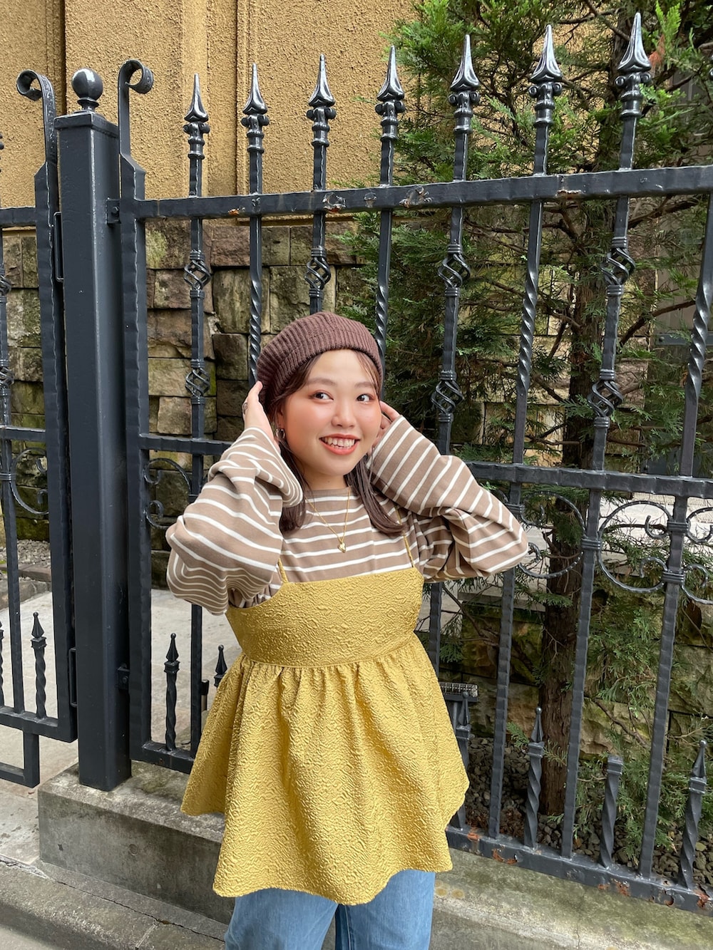 イエロー系のキャミソール、ブラウン系のTシャツ/カットソー、ブルー系のデニムパンツを着用したレディースの秋コーディネートの4枚目の写真