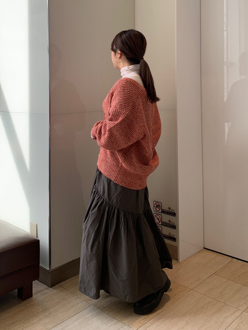 ピンク系のTシャツ/カットソー、オレンジ系のカーディガン/ボレロ、グレー系のスカートを着用したレディースの冬コーディネートの2枚目の写真