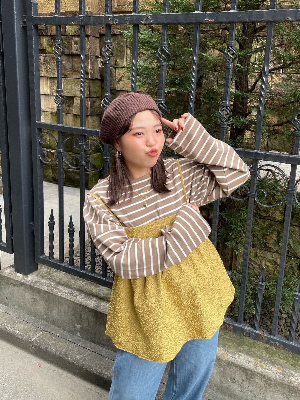 イエロー系のキャミソール、ブラウン系のTシャツ/カットソー、ブルー系のデニムパンツを着用したレディースの秋コーディネートの5枚目の写真