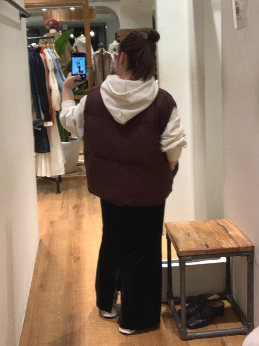 ブラウン系のダウンベスト、ホワイト系のパーカー、ブラック系のスカートを着用したレディースの秋コーディネートの3枚目の写真