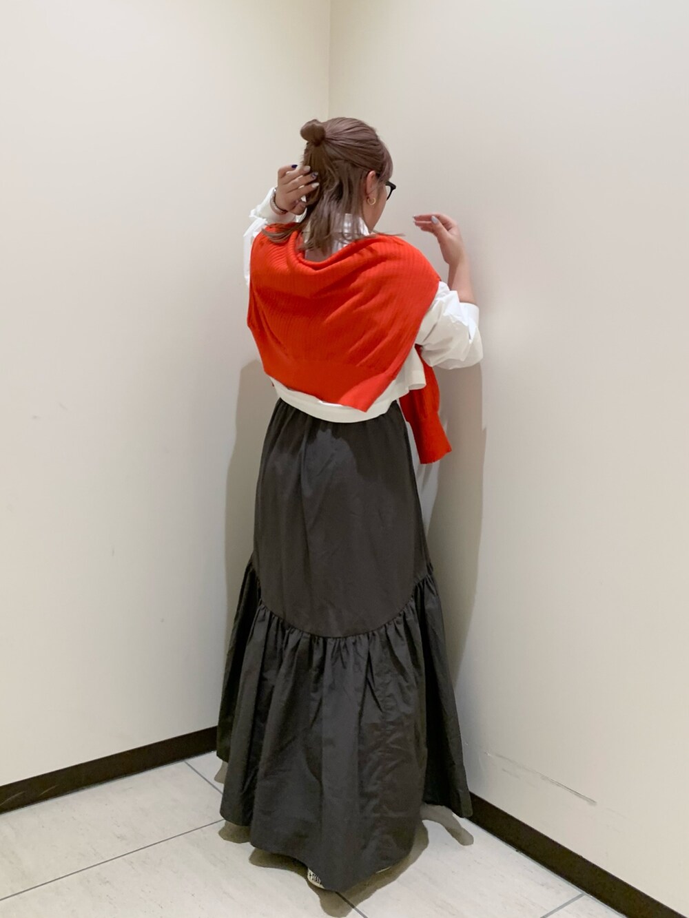 オレンジ系のカーディガン/ボレロ、ホワイト系のシャツ/ブラウス、グレー系のスカートを着用したレディースの春コーディネートの3枚目の写真