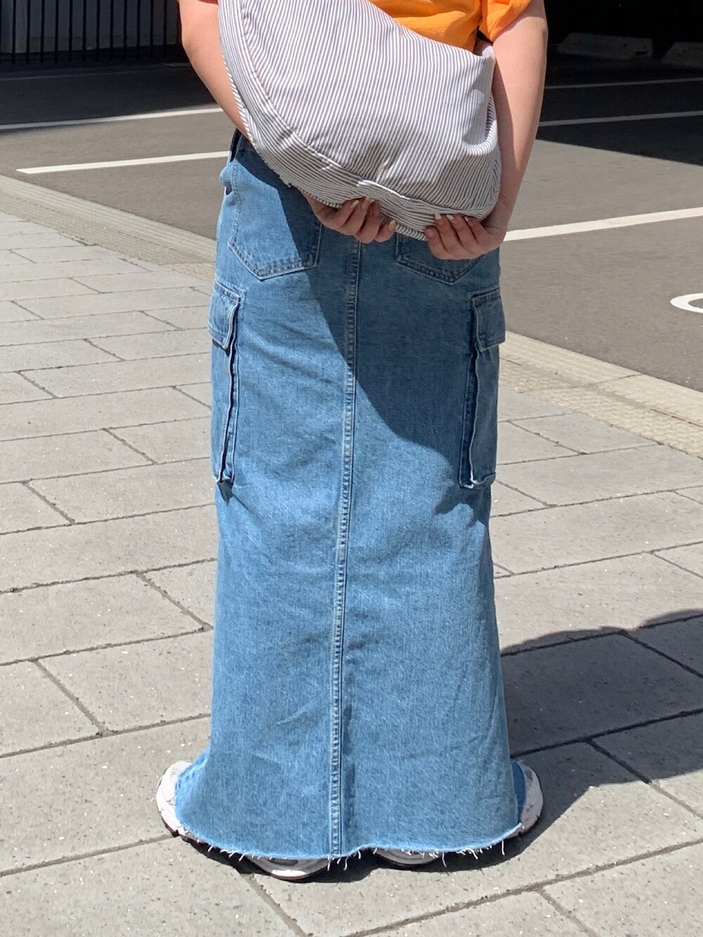 オレンジ系のTシャツ/カットソー、その他のショルダーバッグ、ブルー系のデニムスカートを着用したレディースの春コーディネートの7枚目の写真