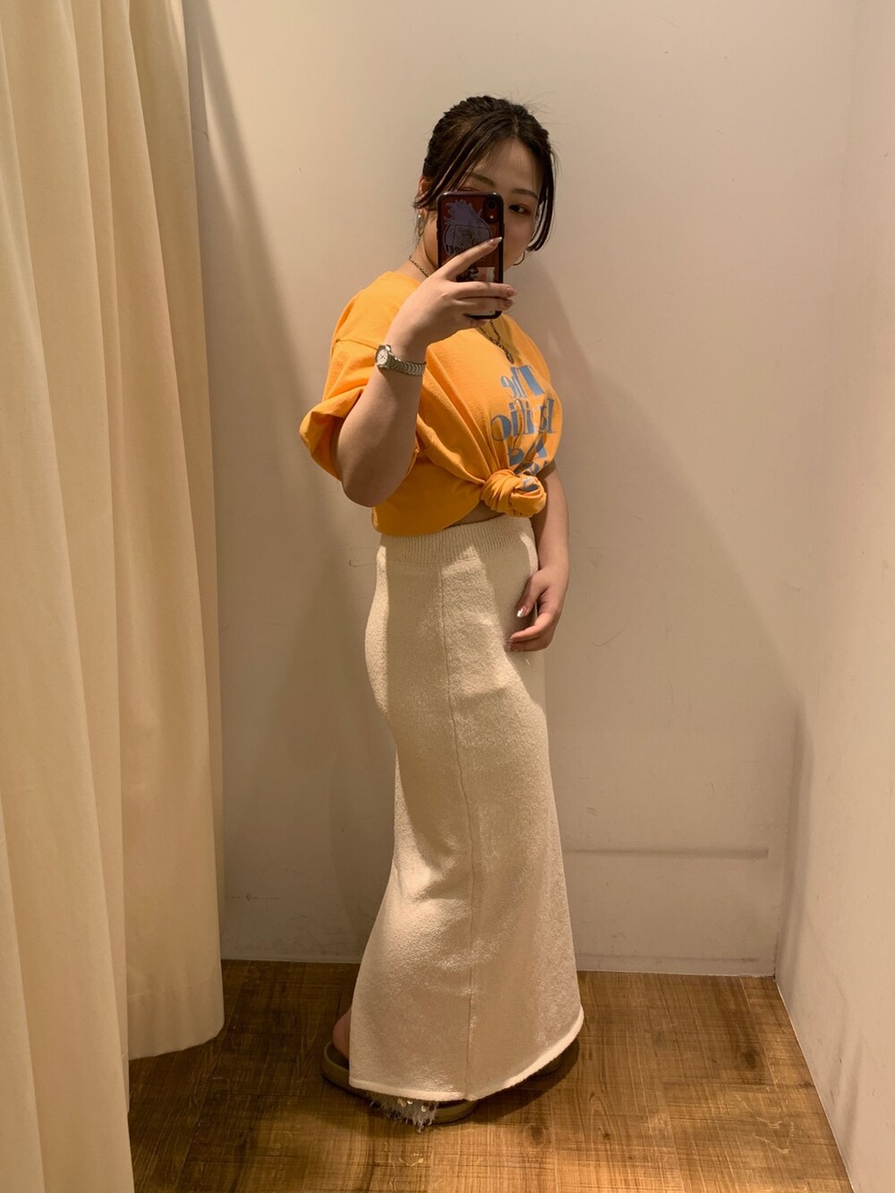 オレンジ系のTシャツ/カットソー、ホワイト系のスカート、ベージュ系のトートバッグを着用したレディースの春コーディネートの2枚目の写真