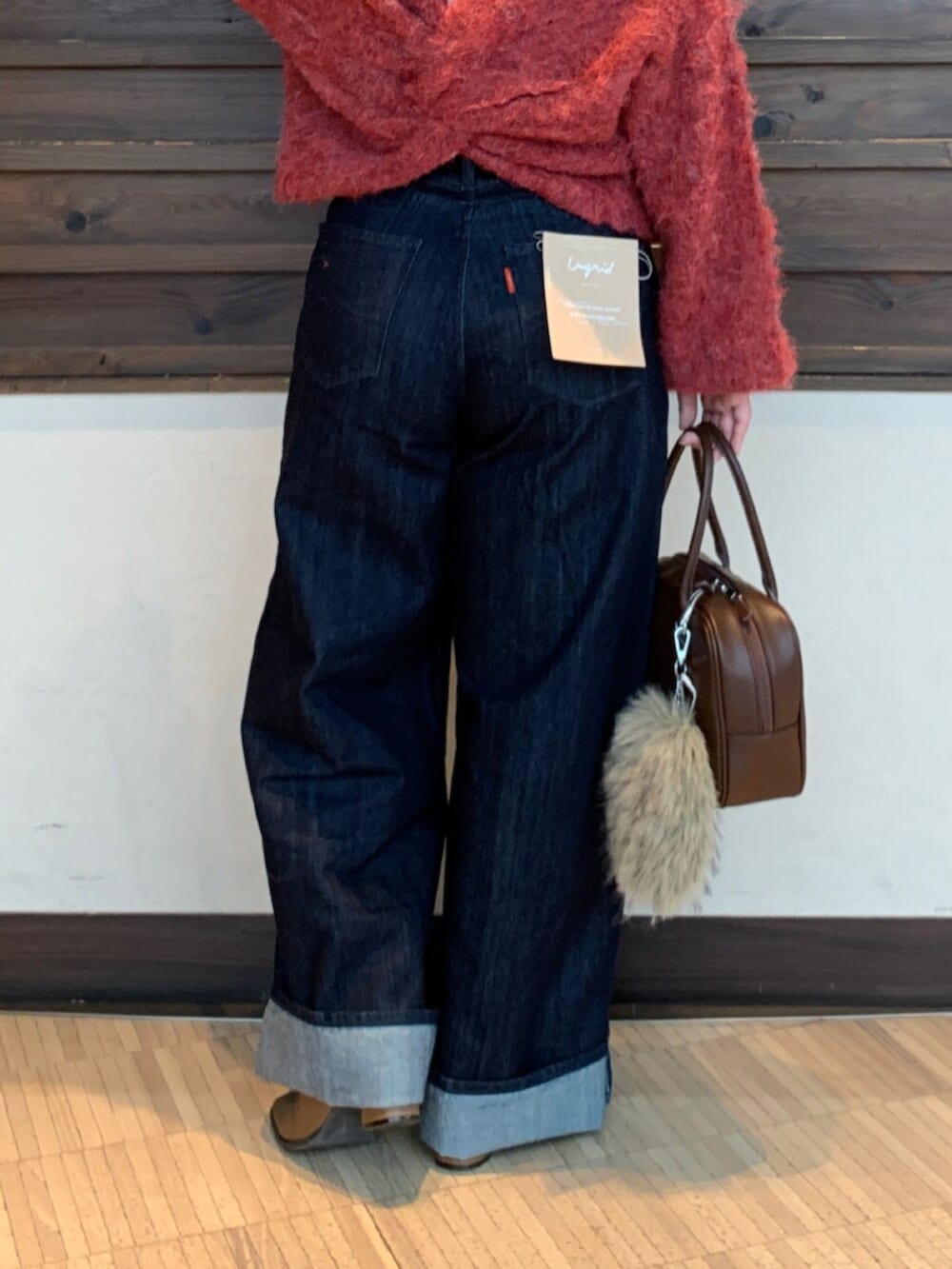 レッド系のニット/セーター、ブルー系のデニムパンツ、ブラウン系のハンドバッグを着用したレディースの秋コーディネートの7枚目の写真